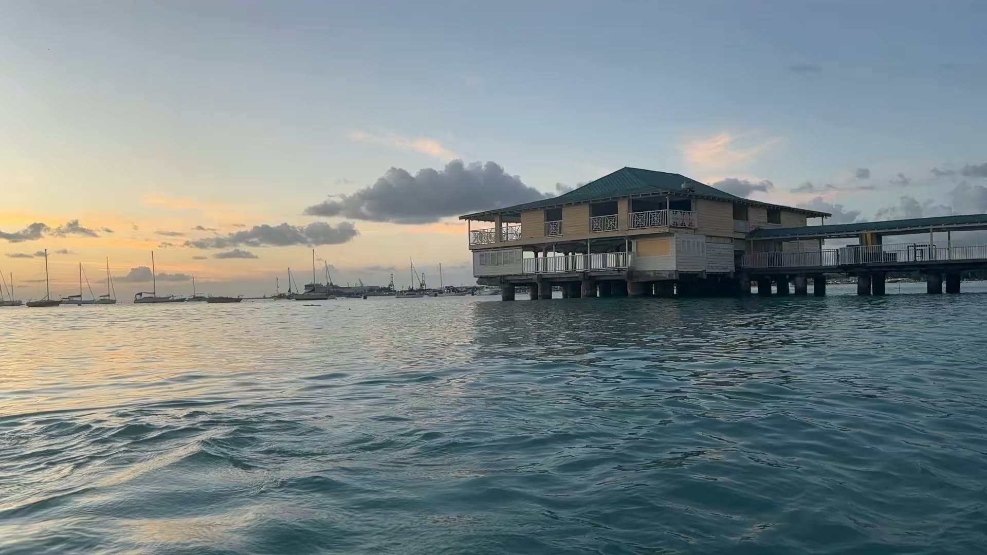 A wooden pavilion on stilts over calm water at sunset in Bridgetown, Barbados